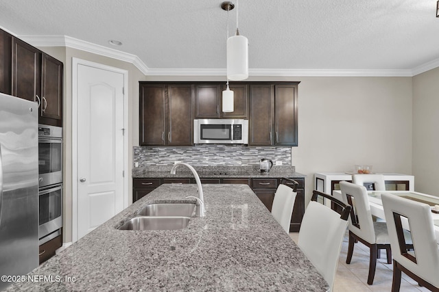 11459 Glenlaurel Oaks Cir, Jacksonville, FL 32257 - kitchen with a sink, stainless steel appliances, crown molding, dark brown cabinetry, and pendant lighting