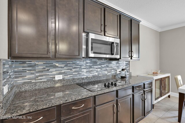 11459 Glenlaurel Oaks Cir, Jacksonville, FL 32257 - kitchen with dark stone countertops, dark brown cabinetry, stainless steel microwave, black electric cooktop, and ornamental molding