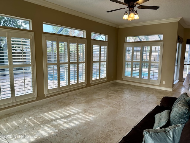 interior space with crown molding, a ceiling fan, baseboards, and a wealth of natural light