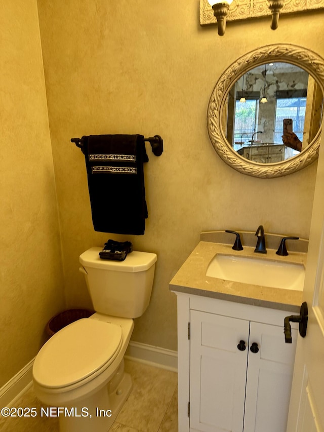 half bathroom with vanity, tile patterned flooring, baseboards, and toilet
