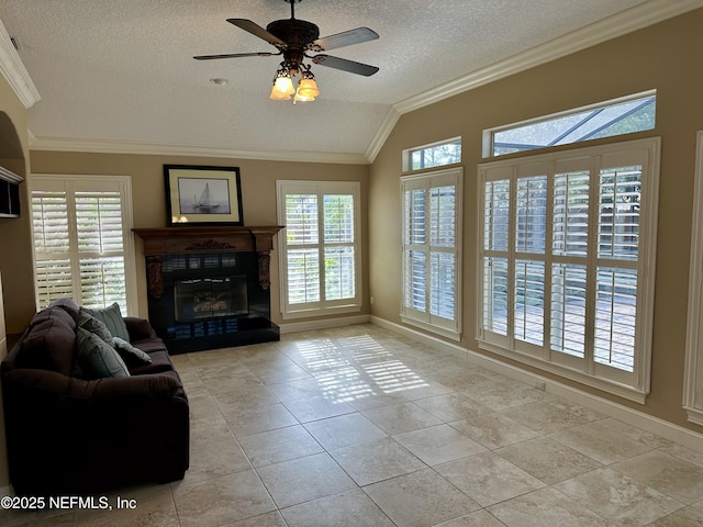 living room with a fireplace, a textured ceiling, plenty of natural light, vaulted ceiling, and ornamental molding