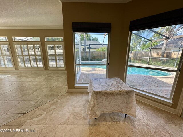 unfurnished dining area with crown molding, a textured ceiling, and baseboards