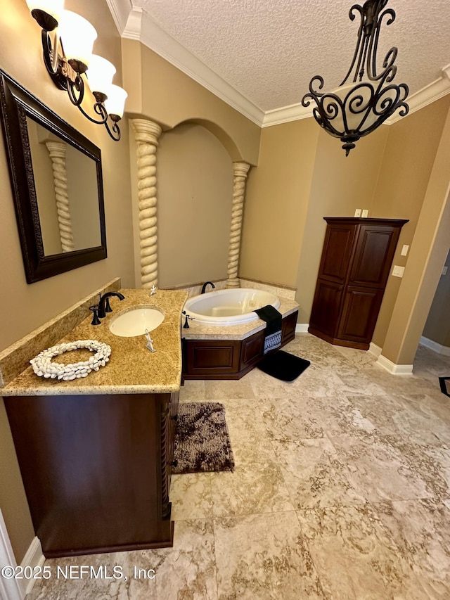 bathroom with a garden tub, ornamental molding, ornate columns, a textured ceiling, and a sink