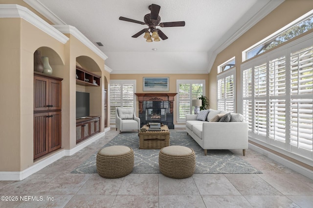 living room with crown molding, a ceiling fan, baseboards, and a glass covered fireplace