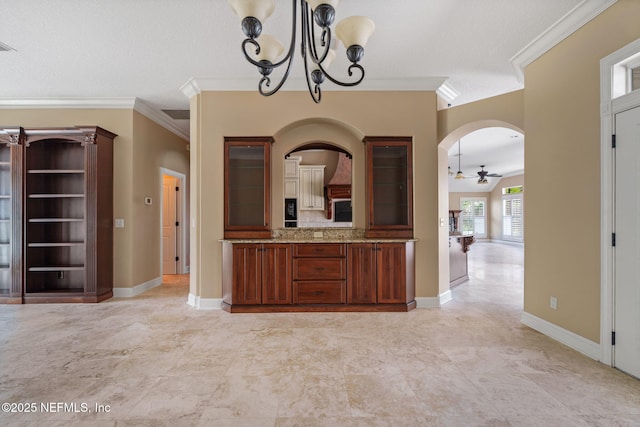 kitchen with light stone countertops, hanging light fixtures, ceiling fan with notable chandelier, ornamental molding, and glass insert cabinets