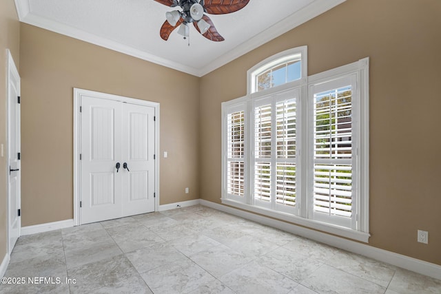 empty room featuring a ceiling fan, baseboards, and ornamental molding