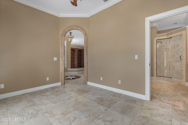 spare room featuring baseboards, ornamental molding, arched walkways, and ceiling fan