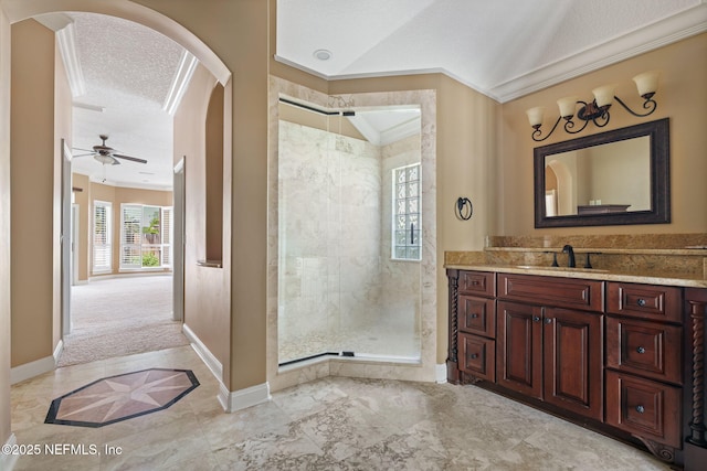 bathroom featuring a tile shower, vanity, a ceiling fan, baseboards, and ornamental molding