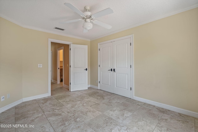 unfurnished bedroom featuring ceiling fan, a textured ceiling, visible vents, ornamental molding, and a closet