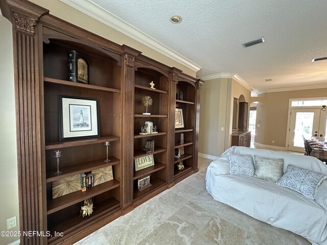 living room with visible vents, ornamental molding, built in features, a textured ceiling, and arched walkways