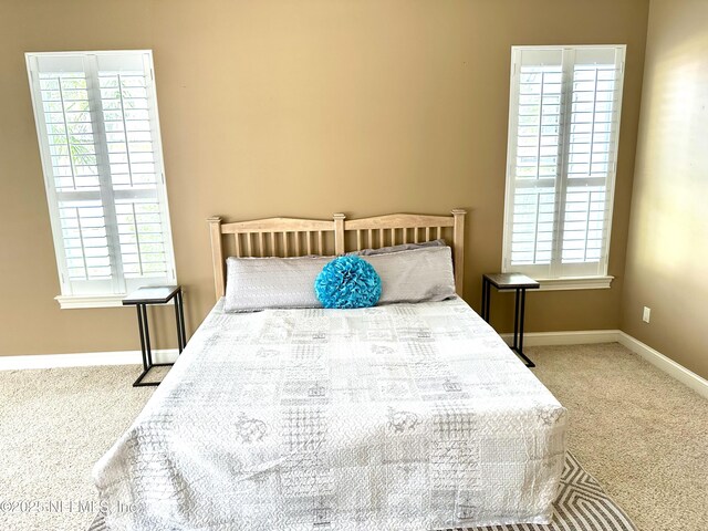 bedroom with baseboards, carpet, and multiple windows