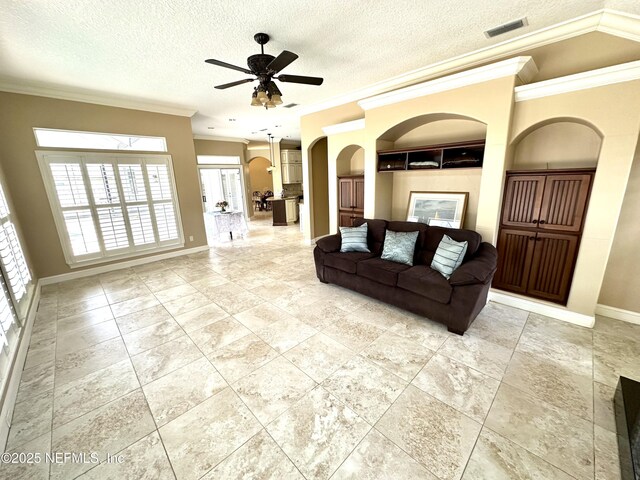 living room featuring crown molding, arched walkways, ceiling fan, and a wealth of natural light