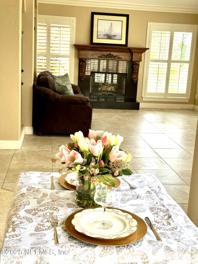 living room featuring crown molding, baseboards, a tiled fireplace, and tile patterned flooring