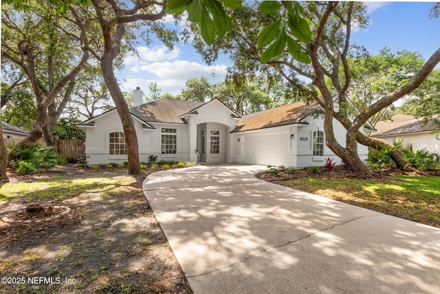 view of front of property with driveway, a chimney, a garage, fence, and stucco siding