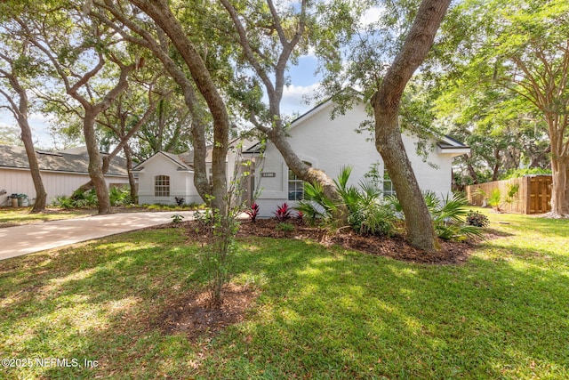 view of front of house featuring fence, stucco siding, and a front lawn