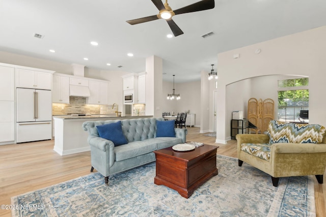 living room featuring visible vents, recessed lighting, light wood finished floors, and ceiling fan with notable chandelier