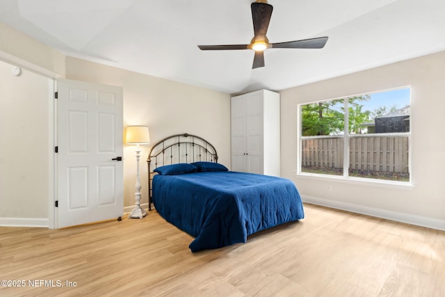 bedroom with baseboards, ceiling fan, and light wood-type flooring