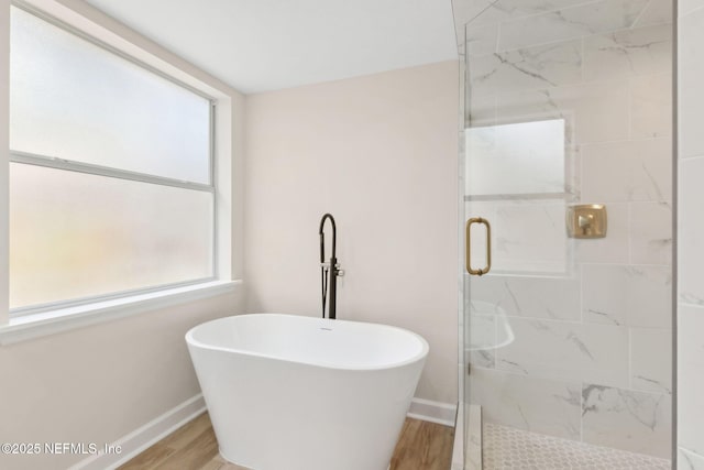 full bathroom with baseboards, a freestanding bath, a stall shower, and wood finished floors