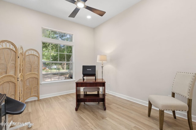 living area featuring a ceiling fan, baseboards, wood finished floors, and a high ceiling