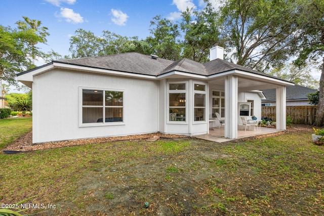 rear view of house featuring fence, roof with shingles, a chimney, a patio area, and a yard