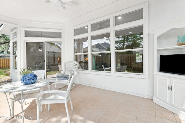 sunroom / solarium with ceiling fan and tile patterned floors