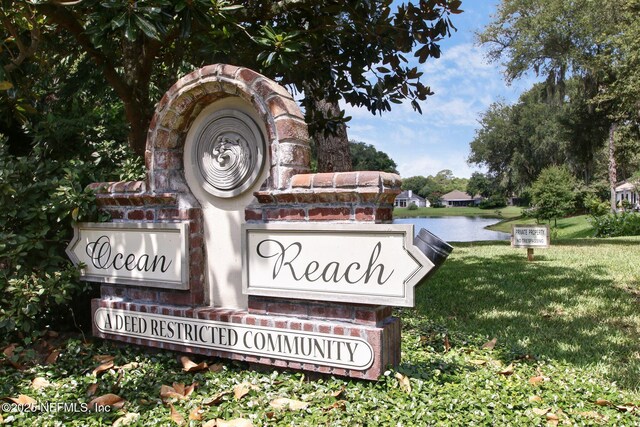 community sign featuring a lawn and a water view