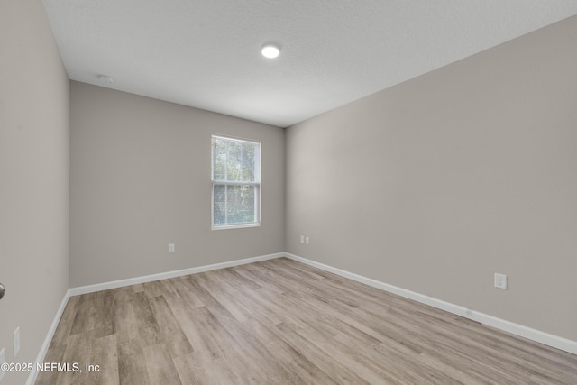 spare room featuring baseboards and light wood-style flooring