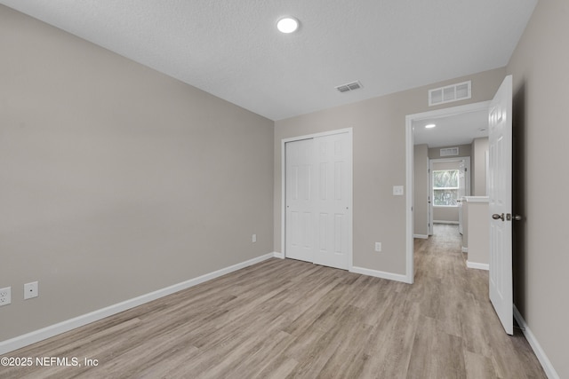 unfurnished bedroom featuring baseboards, light wood finished floors, and visible vents