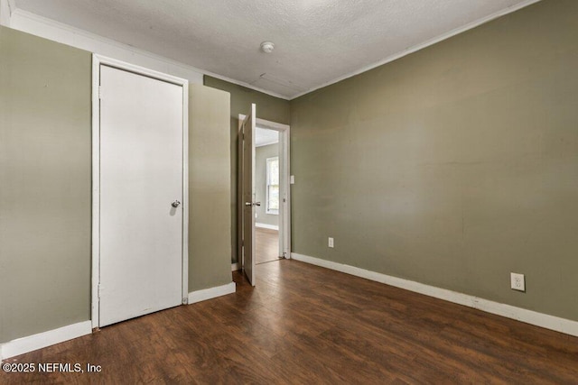 unfurnished bedroom with wood finished floors, a closet, crown molding, and baseboards