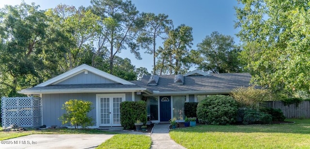 ranch-style home featuring a front lawn, fence, and french doors