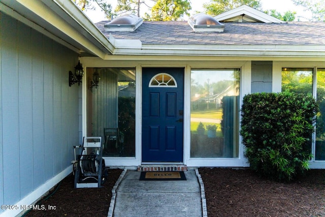 doorway to property with a shingled roof
