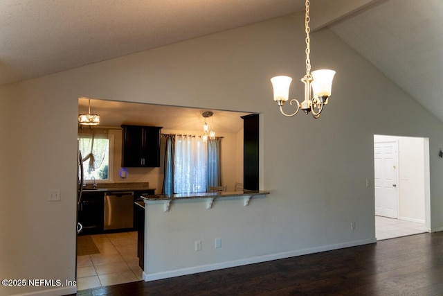 kitchen featuring a breakfast bar area, dishwasher, high vaulted ceiling, an inviting chandelier, and dark stone counters