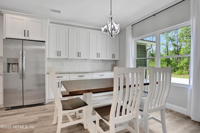 dining space featuring baseboards, visible vents, light wood-style flooring, and a chandelier