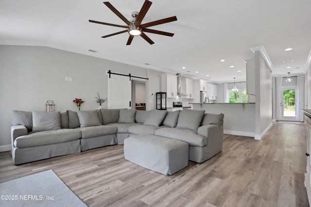 living room with baseboards, a ceiling fan, light wood finished floors, and a barn door