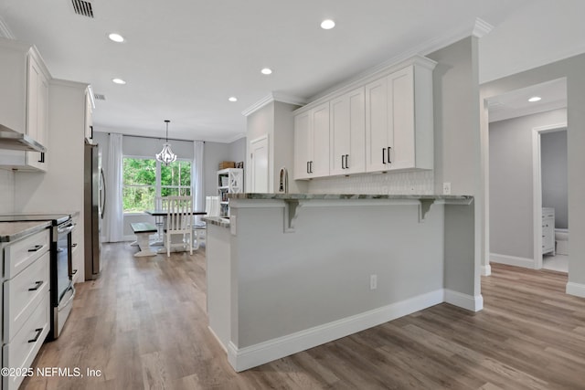 kitchen with crown molding, white cabinets, light stone countertops, stainless steel appliances, and visible vents