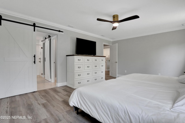 bedroom with crown molding, a barn door, a ceiling fan, baseboards, and wood finished floors