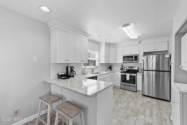 1711 2nd St N, Jacksonville Beach, FL 32250 - kitchen featuring a sink, appliances with stainless steel finishes, white cabinets, and a peninsula