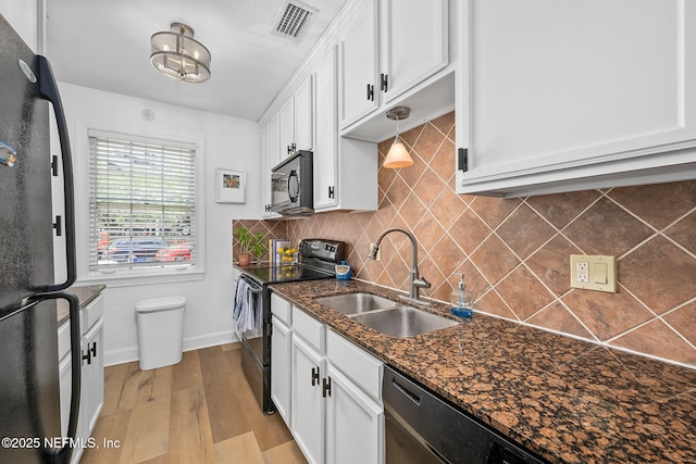 830 Cedar St Unit 830, Jacksonville, FL 32207 - kitchen with white cabinets, a sink, light wood-style flooring, tasteful backsplash, and black appliances