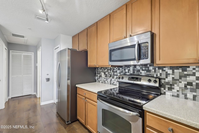 kitchen featuring stainless steel appliances, light countertops, backsplash, dark wood finished floors, and a textured ceiling