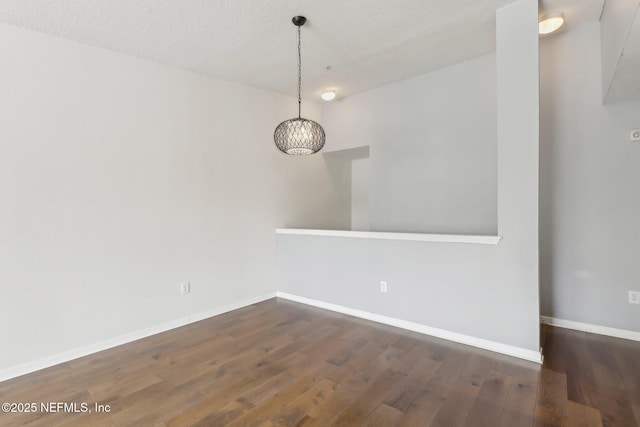 unfurnished dining area with a chandelier, wood finished floors, baseboards, and a textured ceiling