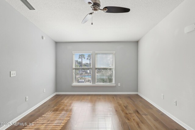 empty room with ceiling fan, a textured ceiling, wood finished floors, and baseboards