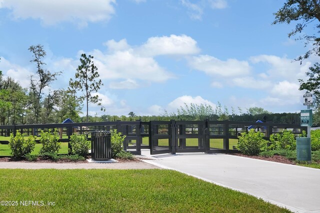 view of gate featuring a lawn and fence