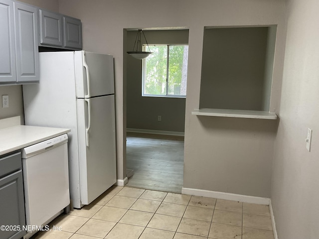 kitchen featuring light countertops, white dishwasher, baseboards, and gray cabinets