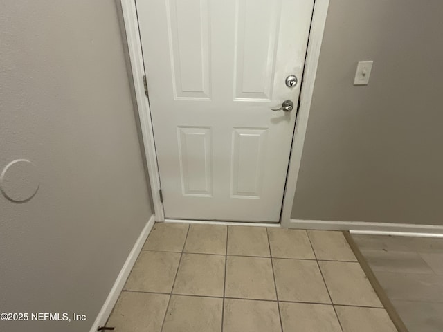 doorway with baseboards and light tile patterned flooring