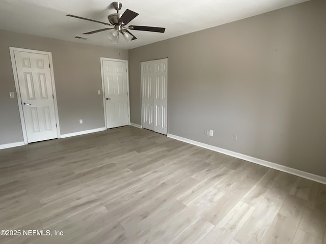 spare room with baseboards, ceiling fan, wood finished floors, and visible vents