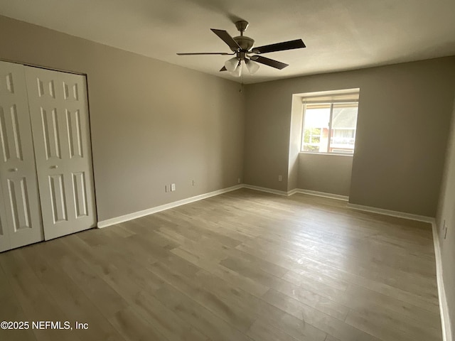 unfurnished bedroom with a ceiling fan, baseboards, wood finished floors, and a closet