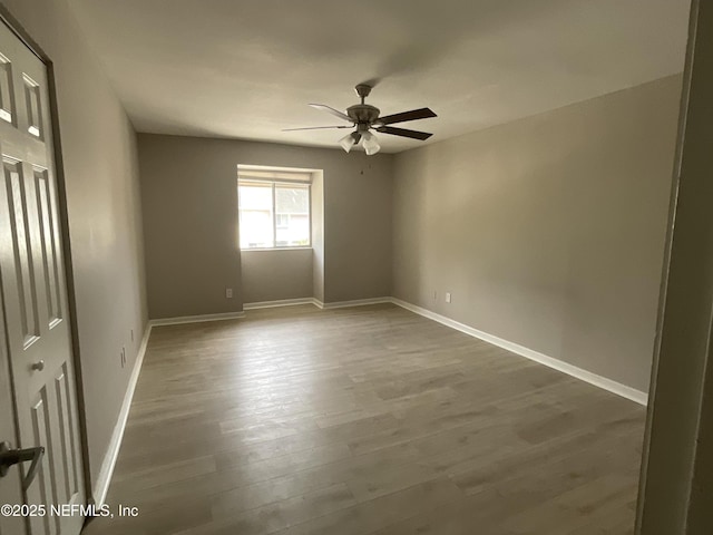 unfurnished room with baseboards, ceiling fan, and dark wood-style flooring