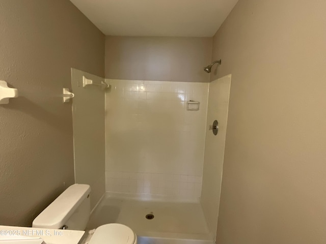 bathroom featuring toilet and a tile shower