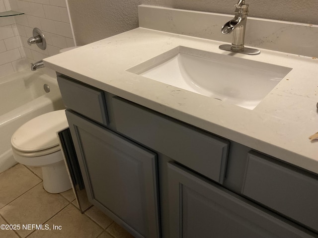 bathroom with a textured wall, washtub / shower combination, vanity, toilet, and tile patterned floors