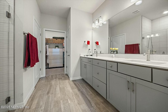 21 Yellow Iris Ct, Ponte Vedra, FL 32081 - bathroom featuring double vanity, wood finished floors, baseboards, tiled shower, and a sink